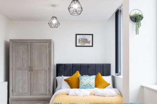 een slaapkamer met een bed met gele en blauwe kussens bij Bright Stylish Studio Apartment in Old Trafford in Manchester