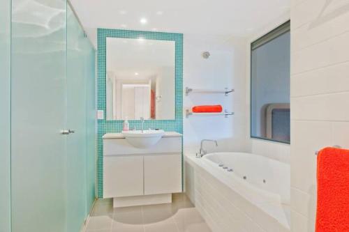 La salle de bains est pourvue d'une baignoire, d'un lavabo et d'un miroir. dans l'établissement Peppers Salt Resort & Spa 2 br luxury spa suite, à Kingscliff