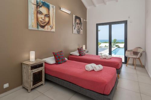 two beds in a room with a view of the ocean at La Villa KAZ DEL MAR in Sainte-Anne
