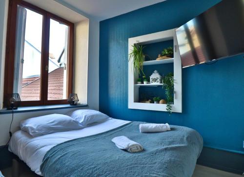 a bedroom with blue walls and a bed with towels on it at Studio de 30m² hypercentre très calme in Montbéliard