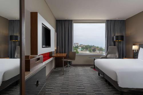 a hotel room with two beds and a television at Radisson Blu Okoume Palace Hotel, Libreville in Libreville