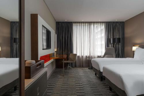 a hotel room with two beds and a desk at Radisson Blu Okoume Palace Hotel, Libreville in Libreville
