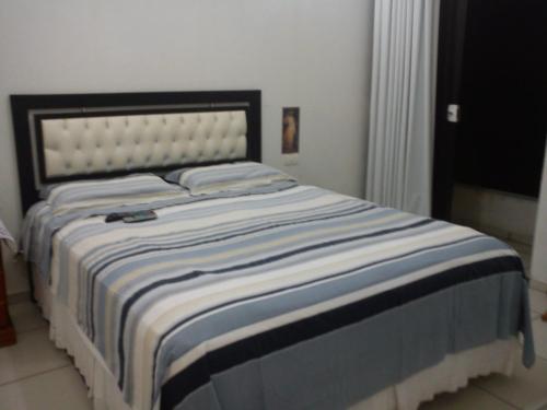 a bed with a blue and white striped blanket on it at Sol e Mar 850mts do mar Ingleses Satinho in Florianópolis