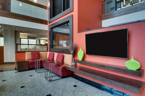 a lobby with a red wall with a flat screen tv at Drury Inn & Suites Evansville East in Evansville