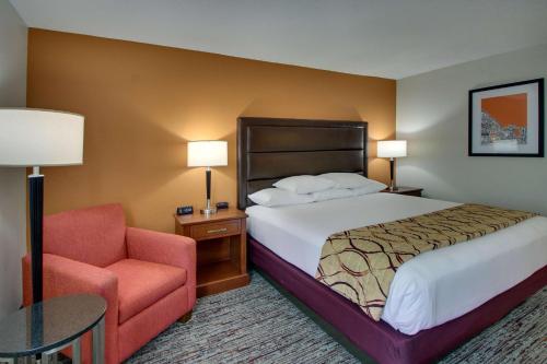 a hotel room with a bed and a chair at Drury Inn & Suites Evansville East in Evansville