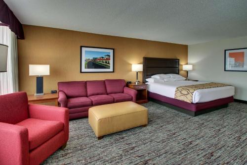 a hotel room with a bed and a couch and chair at Drury Inn & Suites Evansville East in Evansville