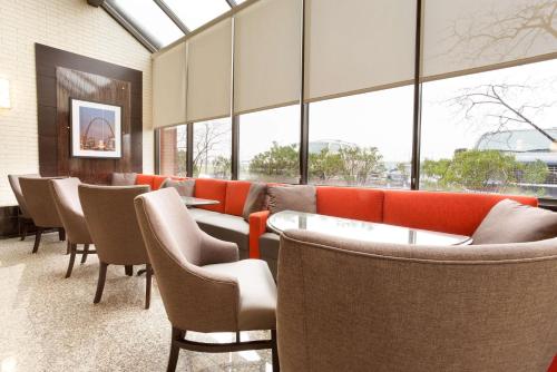 a waiting room with chairs and tables and windows at Drury Inn & Suites St. Louis Airport in Edmundson