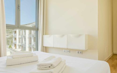 1 dormitorio con toallas blancas en una cama con ventana en Las Aliagas Confort, en Latas