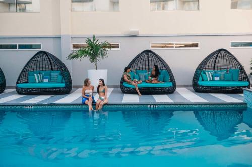 een groep mensen die rond een zwembad in een hotel zitten bij OHANA Waikiki East by OUTRIGGER in Honolulu