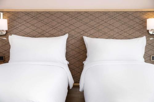 two beds in a hotel room with white pillows at Radisson Blu Resort Al Hoceima in Al Hoceïma