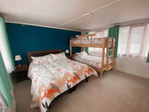 1 dormitorio con 2 literas y pared azul en Indomito Sur Hostel, en Punta Arenas