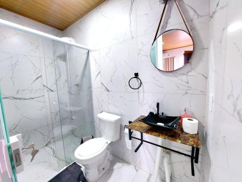 uma casa de banho com um WC, um lavatório e um espelho. em Aconchego Sol e Mar em Navegantes