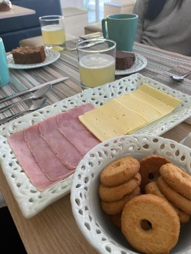 a table with a plate of meat and donuts and cheese at Indomito Sur Hostel in Punta Arenas