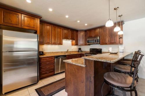 a kitchen with wooden cabinets and a stainless steel refrigerator at Condos with Ski Locker and Vail Mountain Views in Vail