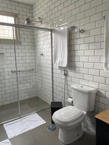 uma casa de banho branca com um WC e um chuveiro em Casa da Árvore Bertioga em Bertioga