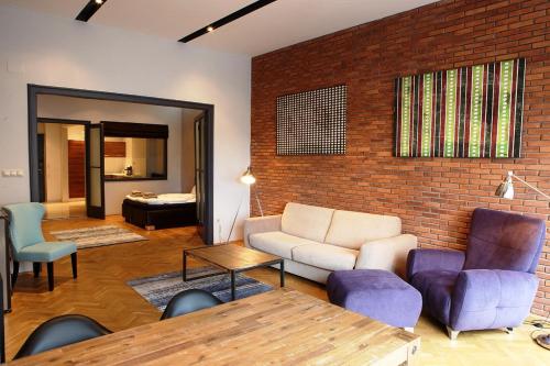sala de estar con sofá, sillas y pared de ladrillo en New Design Apartment - Fashion Street, en Budapest