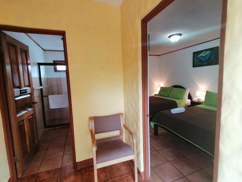 - une chambre avec un lit, une chaise et un miroir dans l'établissement Hotel Santa Fe B&B, à Monteverde Costa Rica