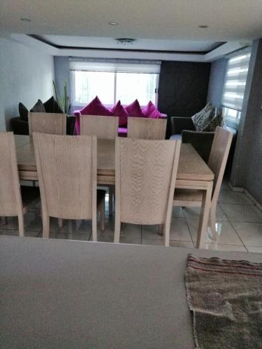 uma sala de jantar com uma mesa e cadeiras com almofadas cor-de-rosa em Casa completa para 8 en Coacalco SuperB em Cidade do México