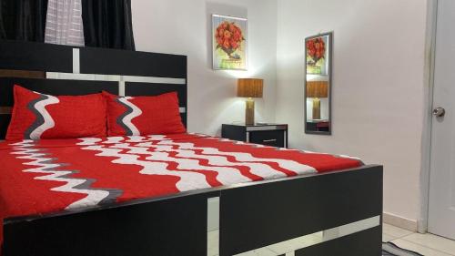 a bedroom with a bed with a red and white comforter at 3 bedrooms with pool & Power inverter near Malecon in La Francia