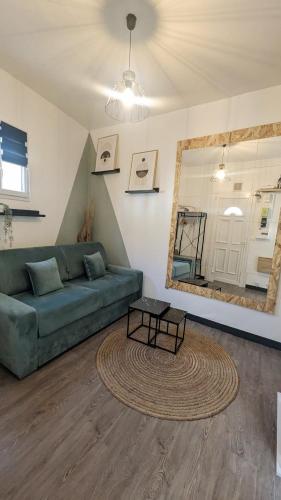 a living room with a green couch and a mirror at *Ça me convient* Studio Chaleureux in Villejuif