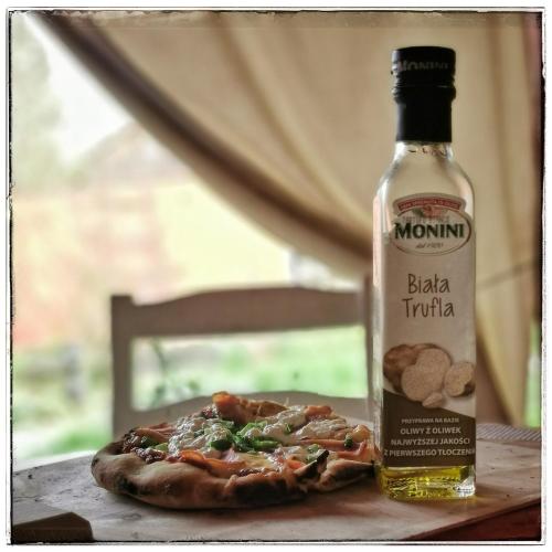 a bottle of alcohol next to a pizza on a table at Cinderella Guitars in Czartoria