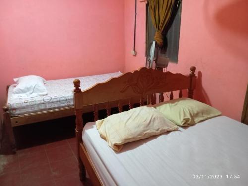 2 camas individuales en una habitación con paredes rosas en Hostal Maria, en Rivas