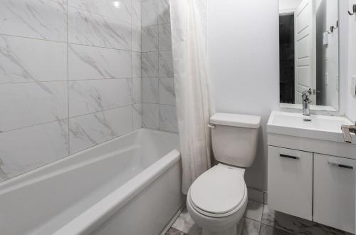 een witte badkamer met een toilet, een bad en een wastafel bij Two bedrooms in 2 floors apartment - 101 in Montreal