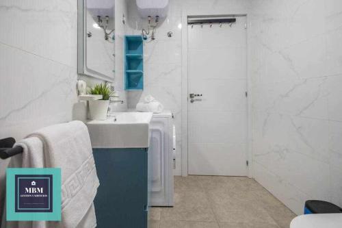 a white bathroom with a sink and a shower at Playa Verde Las Canteras in Las Palmas de Gran Canaria