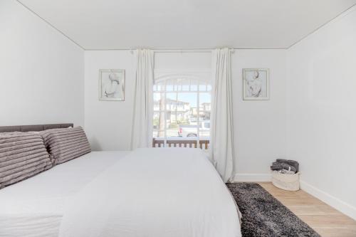 a white bedroom with a white bed and a window at Lovely White Beach House in Redondo Beach