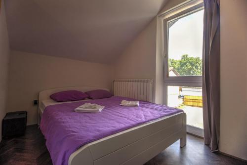 a bedroom with a bed with purple sheets and a window at Hostel Fair and Square in Belgrade