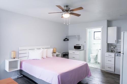 a white bedroom with a bed and a ceiling fan at Poplars Motel on the lake in Osoyoos