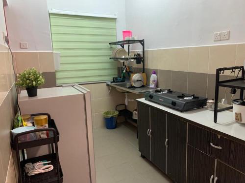 una cucina con lavandino e piano cottura di ALEENA STAYCATION @ APARTMENT TOK PELAM PANTAI BATU BURUK a Kuala Terengganu