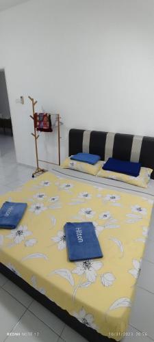 a large bed with a yellow and blue bedspread at Nizmar Inn 2 Guesthouse & Homestay in Gambang