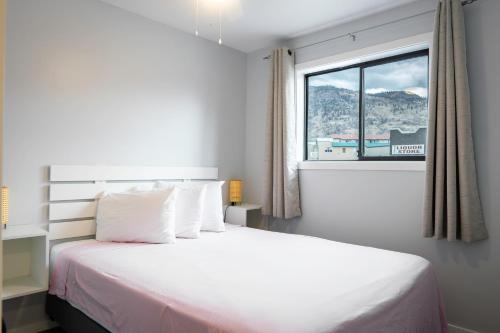 a bedroom with a white bed with a window at Poplars Motel on the lake in Osoyoos