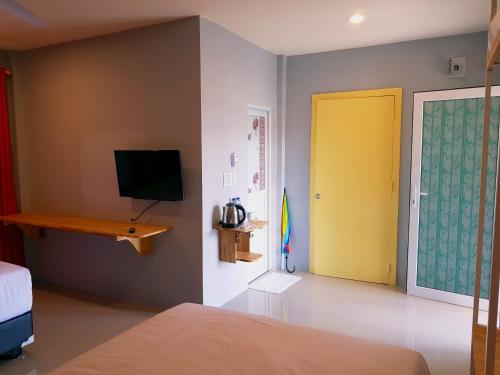 a bedroom with a yellow door and a television at CHEAGIA Resort at Sitinjo near Sidikalang in Hutamanik