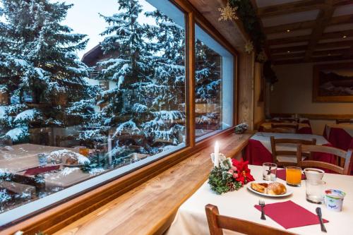 ein Esszimmer mit einem Weihnachtsbaum, durch ein Fenster gesehen in der Unterkunft Hotel Sauze in Sauze dʼOulx