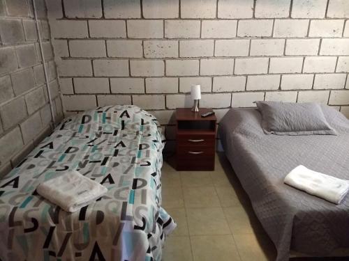- une chambre avec 2 lits et une table de nuit avec un lit et un couvre-lit dans l'établissement Los Duraznillos, à Los Antiguos