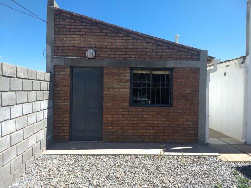 - un bâtiment en briques avec une porte noire dans l'établissement Los Duraznillos, à Los Antiguos