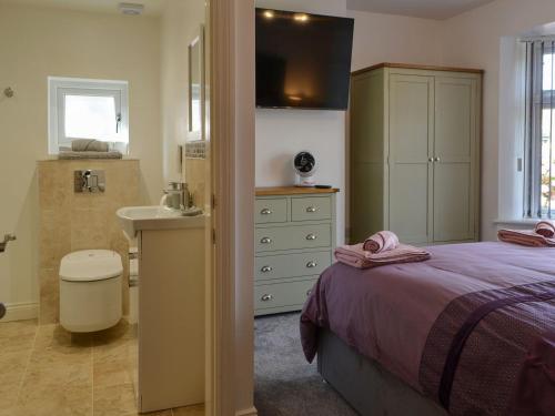 a bedroom with a bed and a bathroom with a sink at Trinity Avenue Cottage in Bridlington