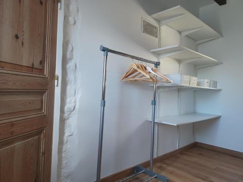 Cette chambre comprend un placard avec des étagères et un balai. dans l'établissement Le Refuge de Normandie avec Spa et Cheminée, à Mesnières-en-Bray