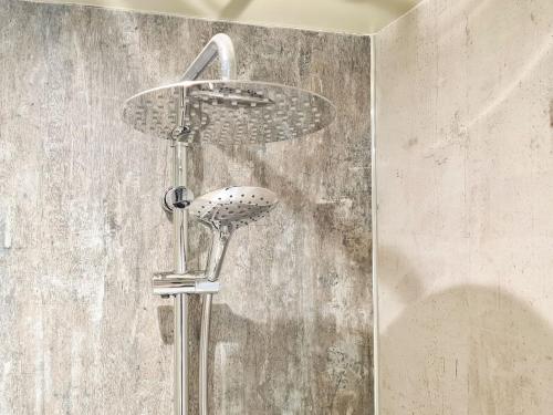 a shower head in a bathroom with a concrete wall at South Riccalton Farm Cottage in Oxnam