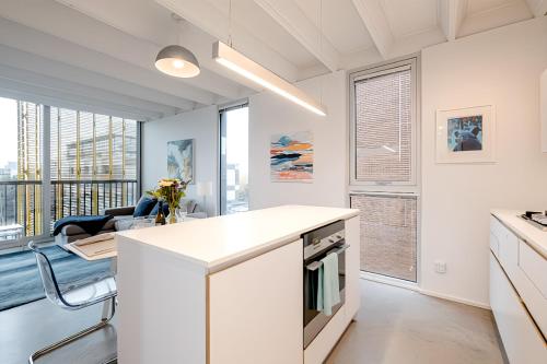 a kitchen with white cabinets and a dining room with a view at Modern, Bright & Central 1-Bed Downtown Apt close to Rogers Arena in Vancouver