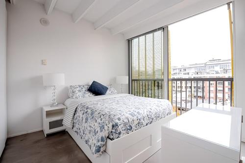 a white bedroom with a bed and a large window at Modern, Bright & Beautiful, 1 Bedroom Downtown Apt with Rooftop Patio in Vancouver