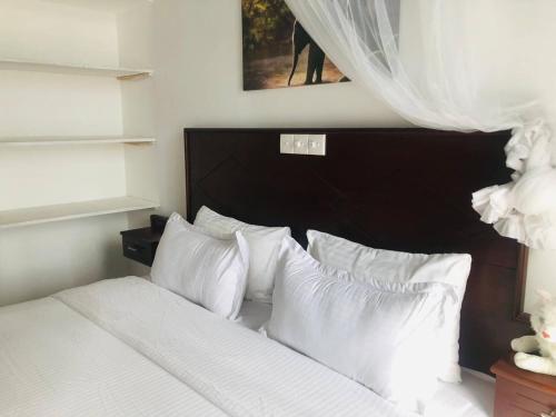 sypialnia z łóżkiem z białą pościelą i poduszkami w obiekcie Ocean Pearl Cottage w mieście Ahungalla