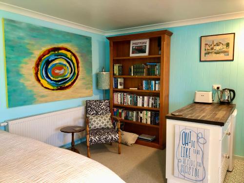 1 dormitorio con estante de libros, 1 cama y 1 silla en Butterfield Beach Studio Car petrol and breakfast provisions included, en Half-moon Bay