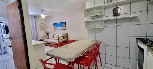 a kitchen and dining room with a table and red chairs at Maceio ferias apto completo a 100 metros da praia in Maceió