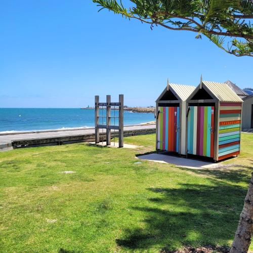 two colorful outhouses sitting on the grass near the beach at Freo Skyhighcentral With Views in Fremantle