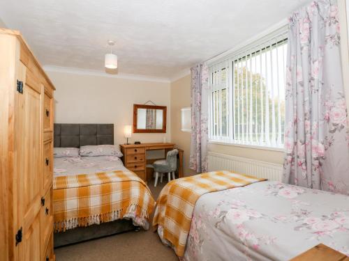 a bedroom with two beds and a desk and a window at Sheppard's Hut in Terrington Saint Clement