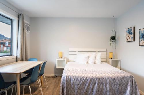 a bedroom with a bed and a table with chairs at Poplars Motel on the lake in Osoyoos