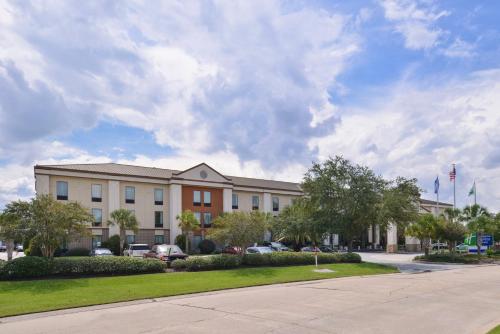 a large building with cars parked in front of it at Holiday Inn Express and Suites New Orleans Airport by IHG in Saint Rose